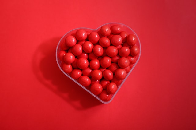 Boîte en forme de cœur sur fond rouge remplie de chocolats 